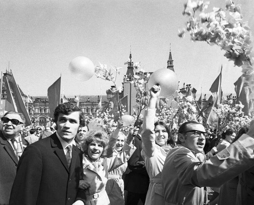 Проходя мимо трибун, празднично одетые демонстранты приветствовали советское правительство, взиравшее на них с трибуны Мавзолея. Там же, на трибуне, стояли фотографы и операторы, и участников шествия заранее инструктировали вести себя перед ними оживленно