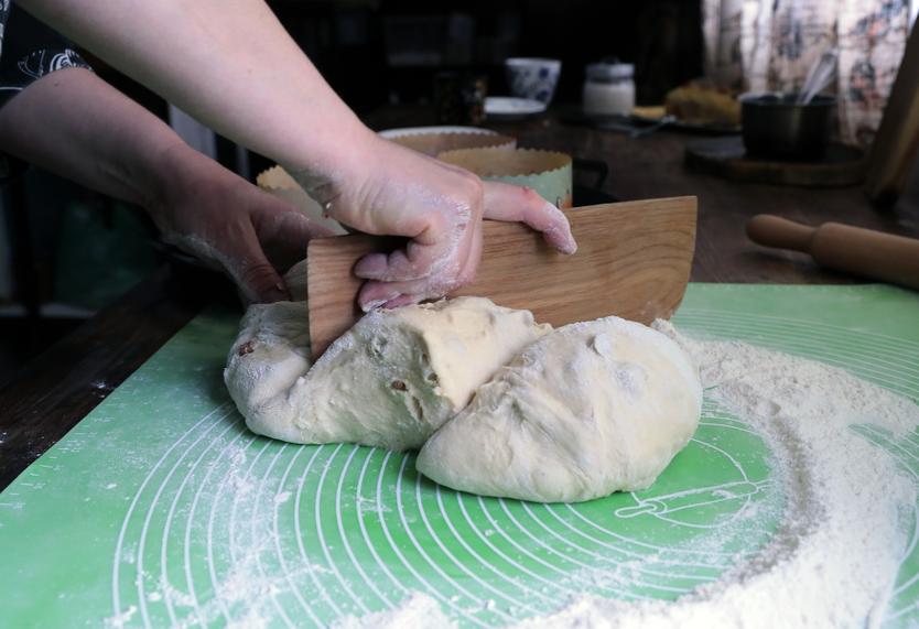 Женщина раскладывает тесто по формам для выпечки домашних куличей