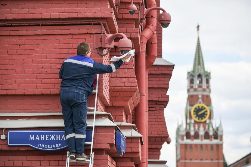 Сотрудник протирает камеру видеонаблюдения на Манежной площади в Москве