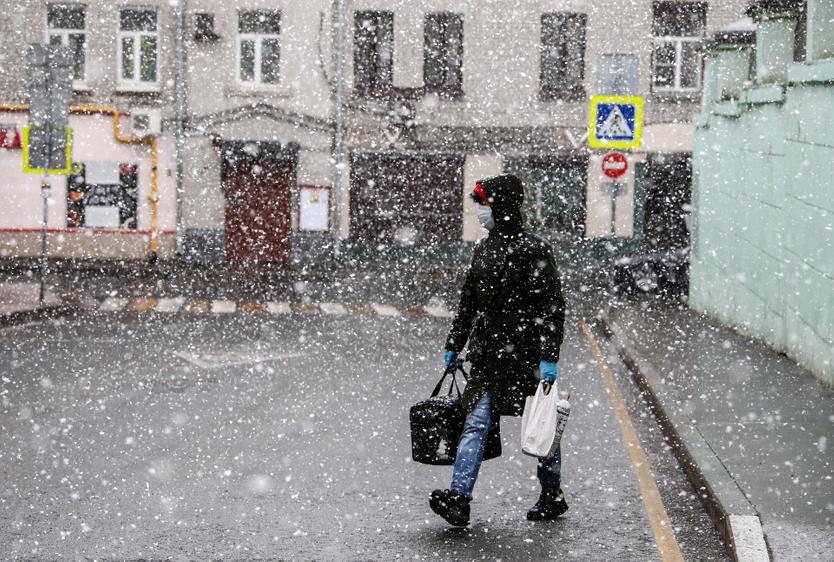 Курьер во время снегопада на одной из улиц города.